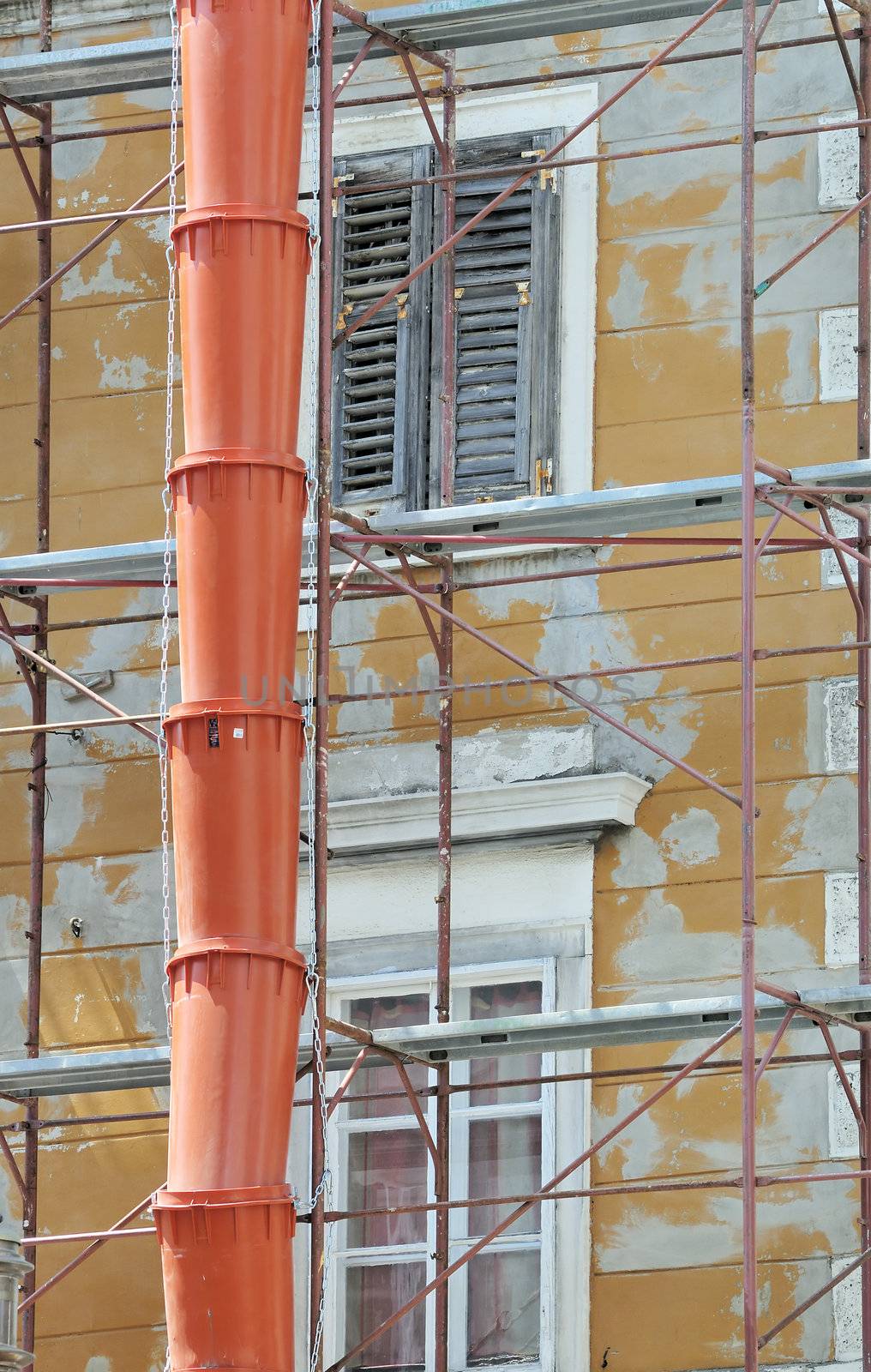 Detail of a construction site with scaffolding and red pipe