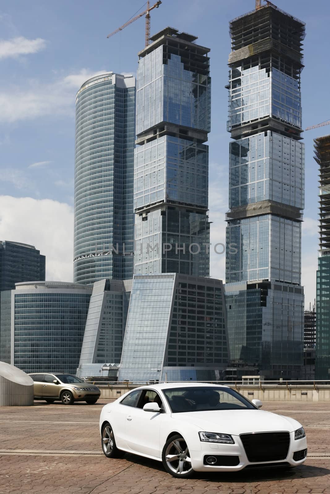 The white automobile on a background of high buildings