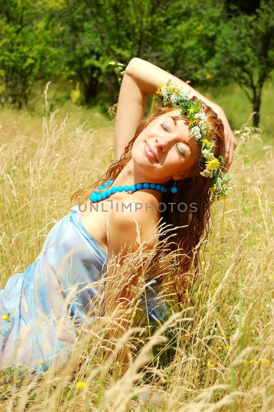 beautiful girl with flower diadem relaxing in fields