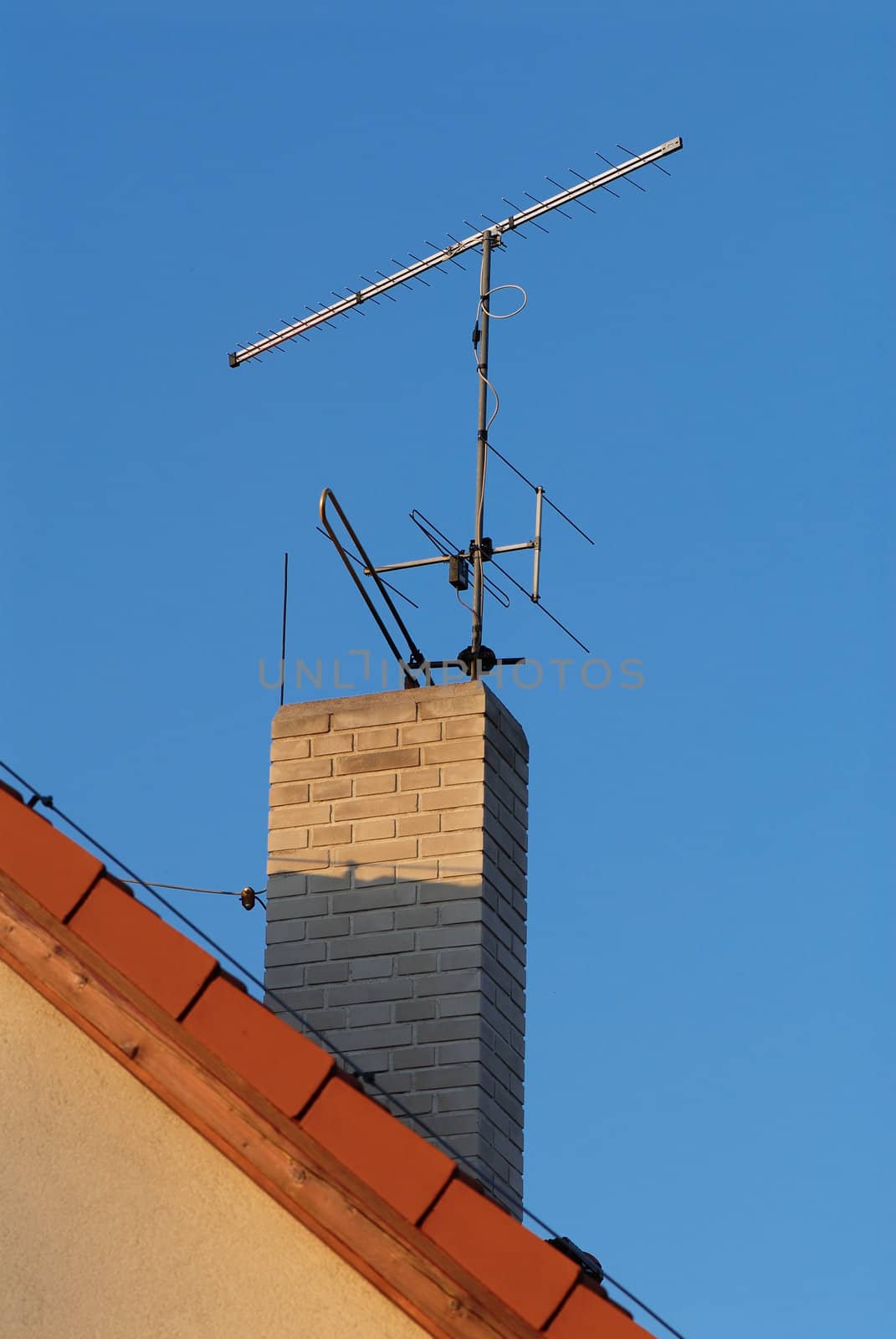 Photo of a chimney of the suburban house with the attached aerials of communication