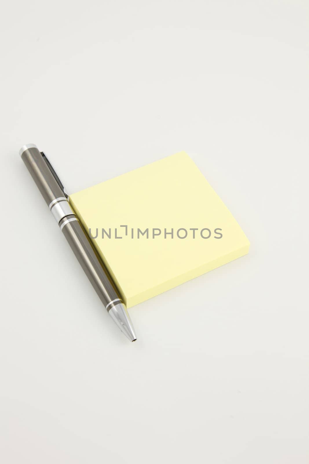 Pen beside a yellow sticky pad