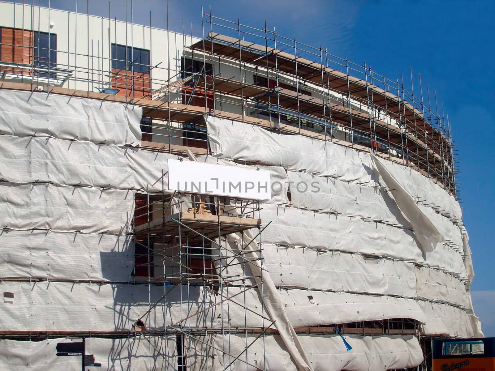A general view of the exterior of a new modern building site development covered in scaffolding and cladding.