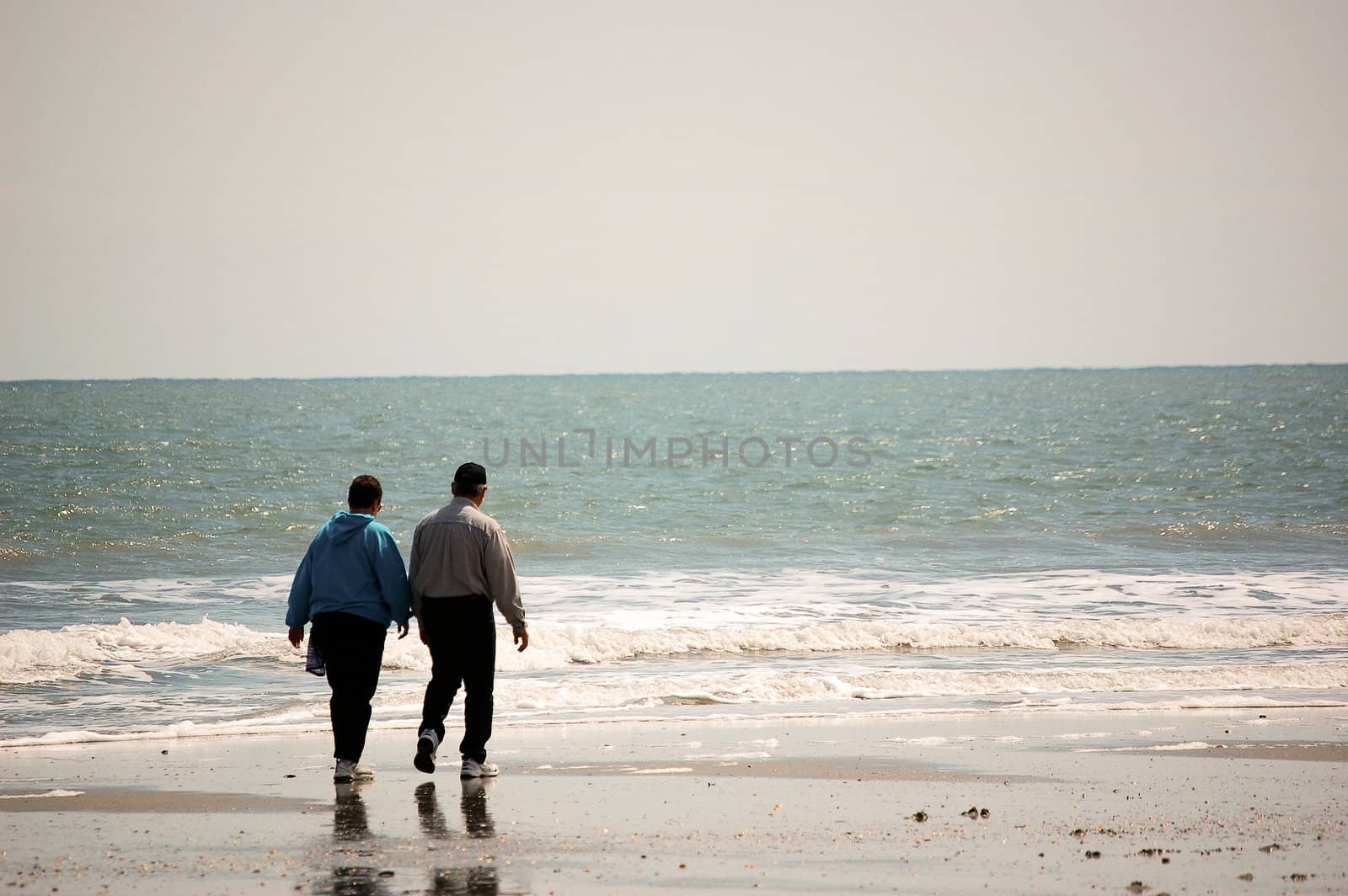 Older Couple Walking On The Beach by RefocusPhoto