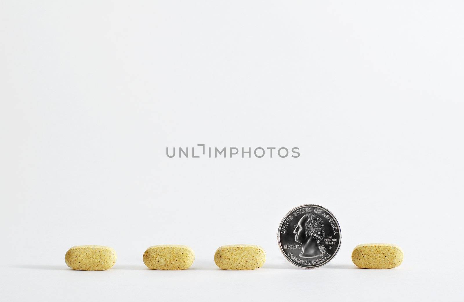 Line of pills, with quarter, against white background.