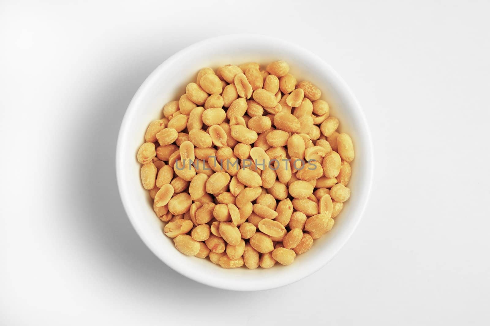 White bowl of peanuts against a white background.