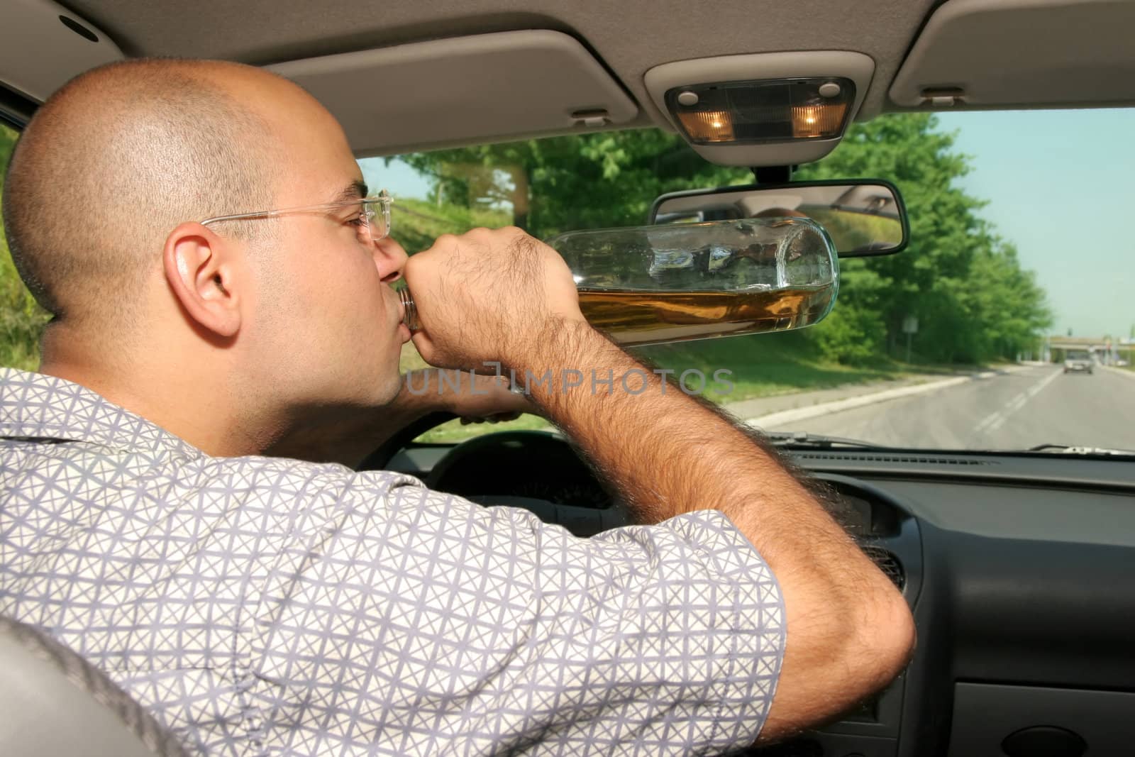 Drunk man sitting in drivers sit and drinking from a bottle