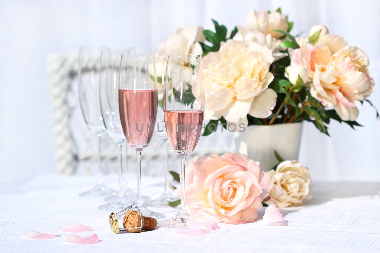 Two glasses filled with pink Champagne with flowers 