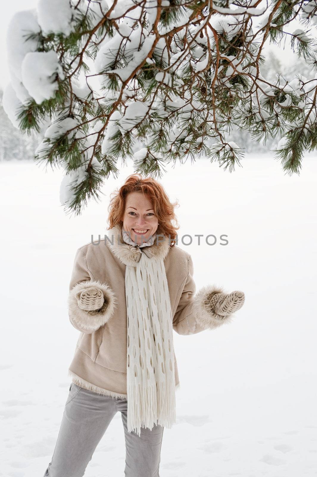 Happy red-haired woman having fun on winters day in forest.