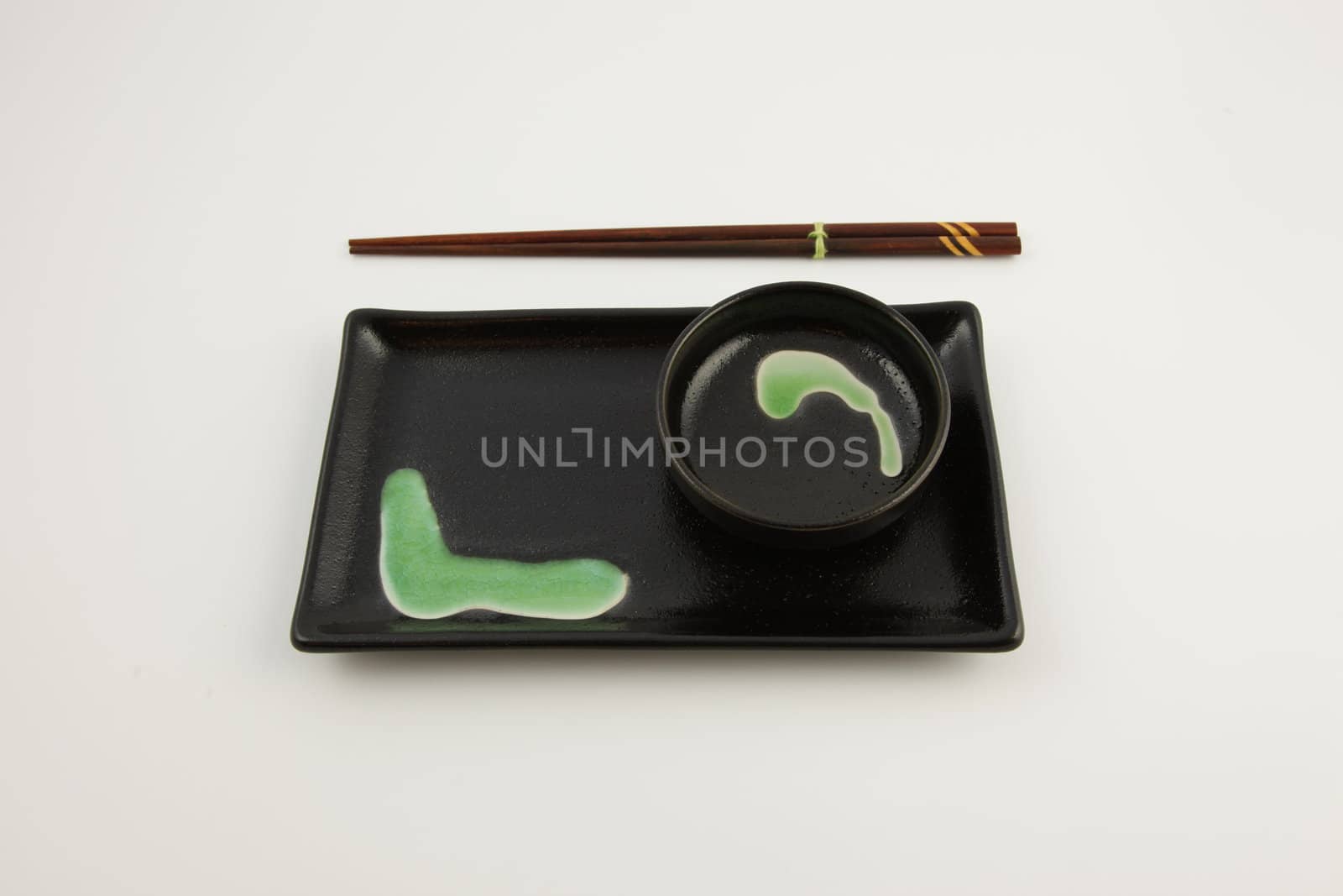 A green and back sushi plate with chopsticks