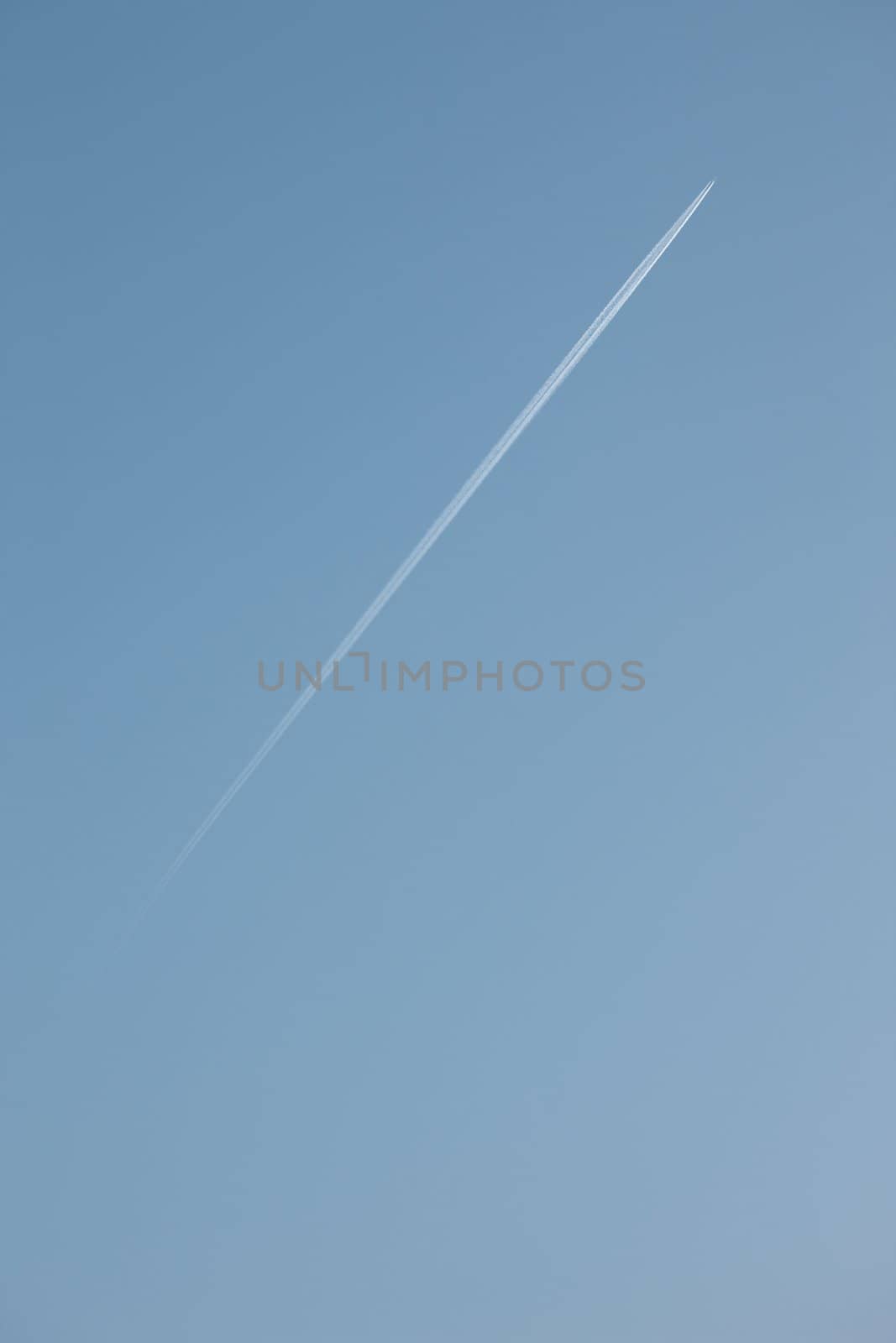 Jet flying high up and leaving vapor trail on a clear blue sky