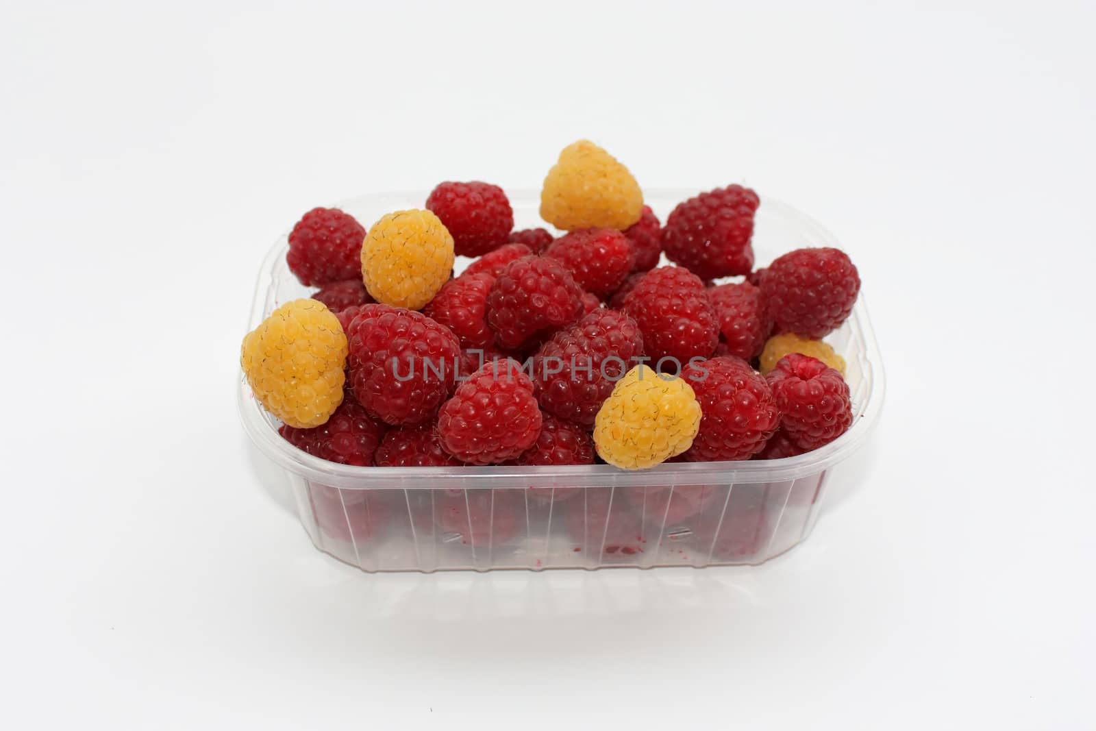fresh raspberries with some yellow berries in a container, isolated