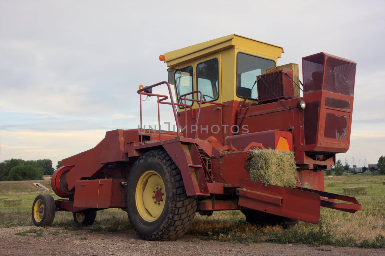 a small square hay baler in a field after harvest, HDR image