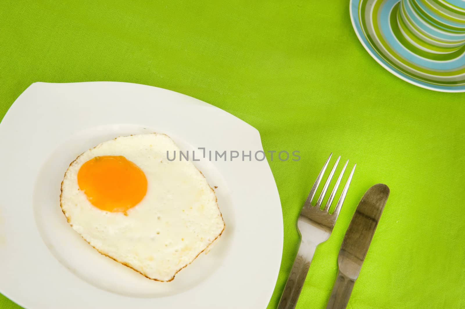 a fried egg on a plate with a fork and a knife