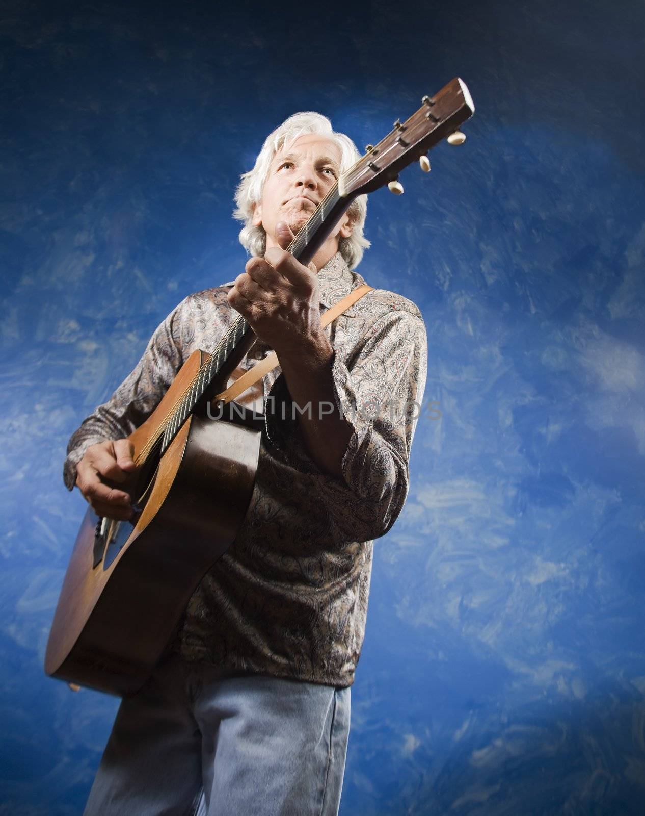 Guitarist with his Instrument in front of a Blue Wall