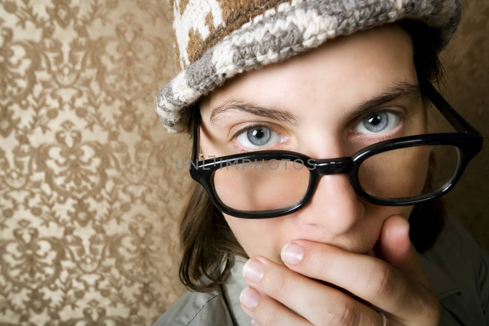 Closeup of Cute Nerdy Woman in a Knit Cap Covering Her Face With Her Hand