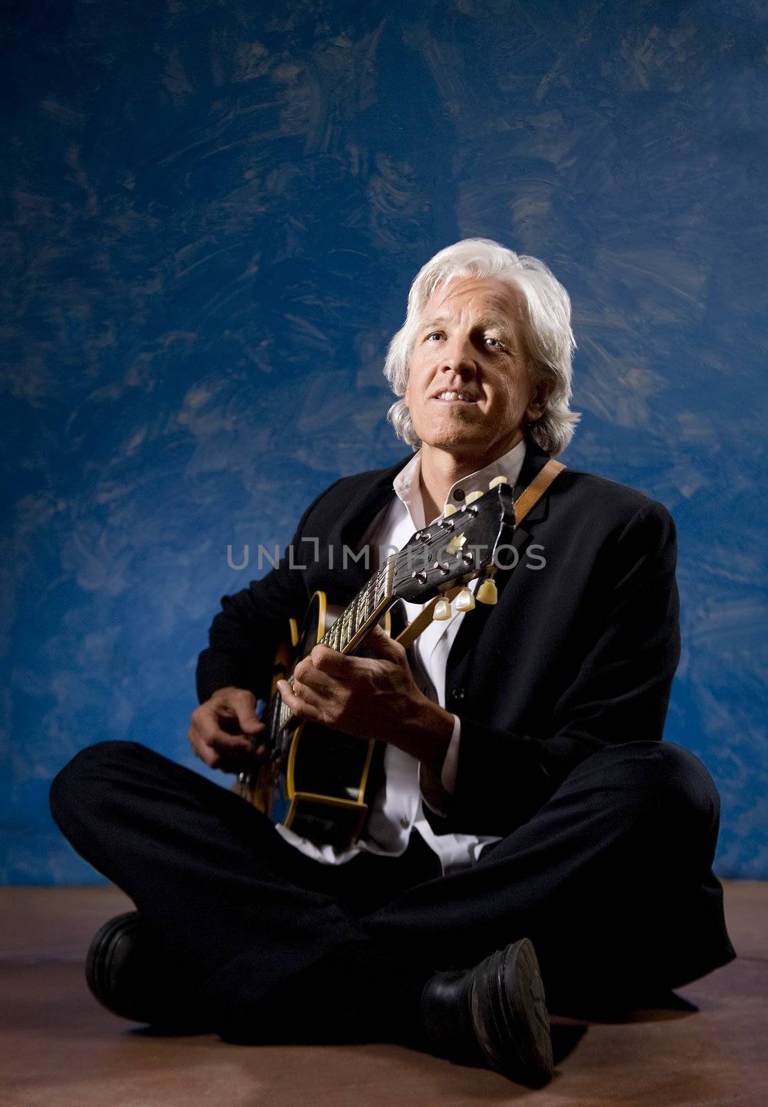 Guitarist with his Instrument in front of a Blue Wall