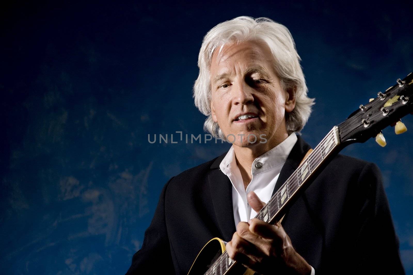 Guitarist with his Instrument in front of a Blue Wall