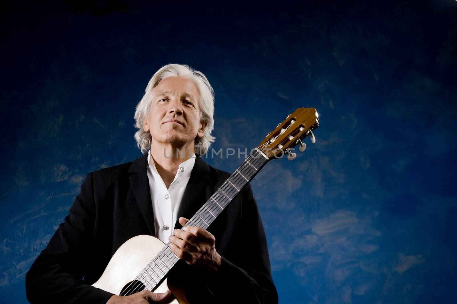 Classical Guitarist with his Instrument in front of a Blue Wall