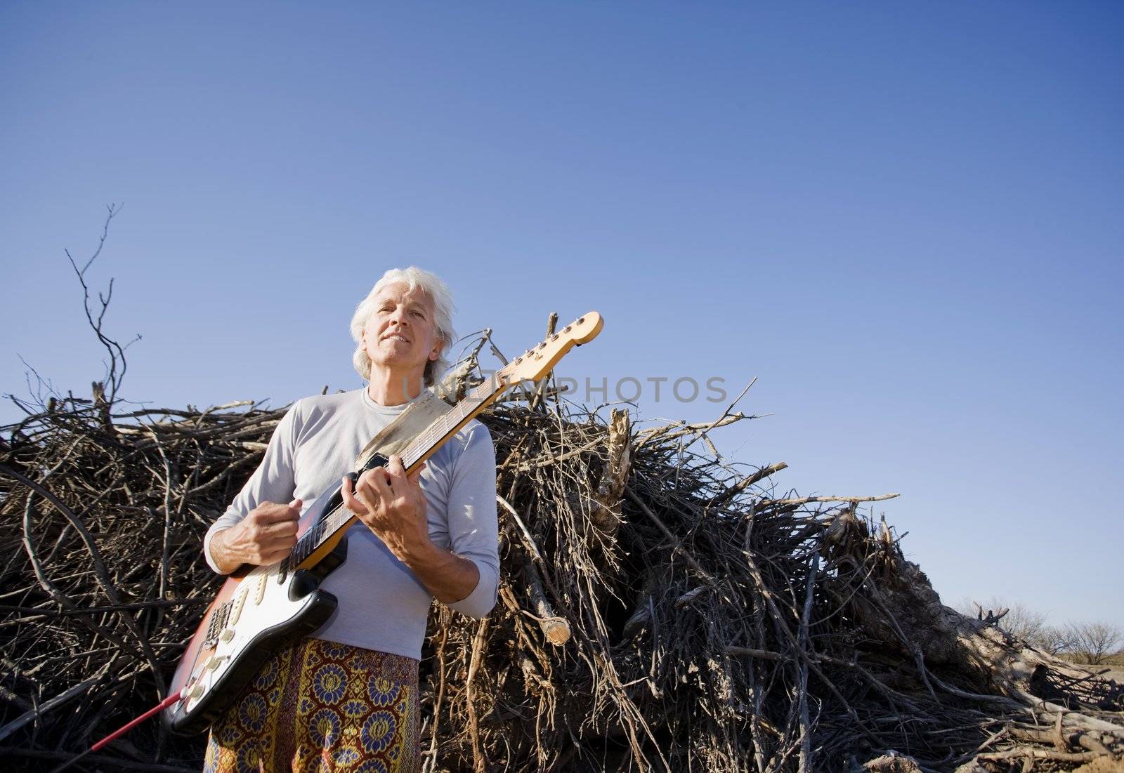 Electric Gutiar Player in Front of a Big Pile of Wood