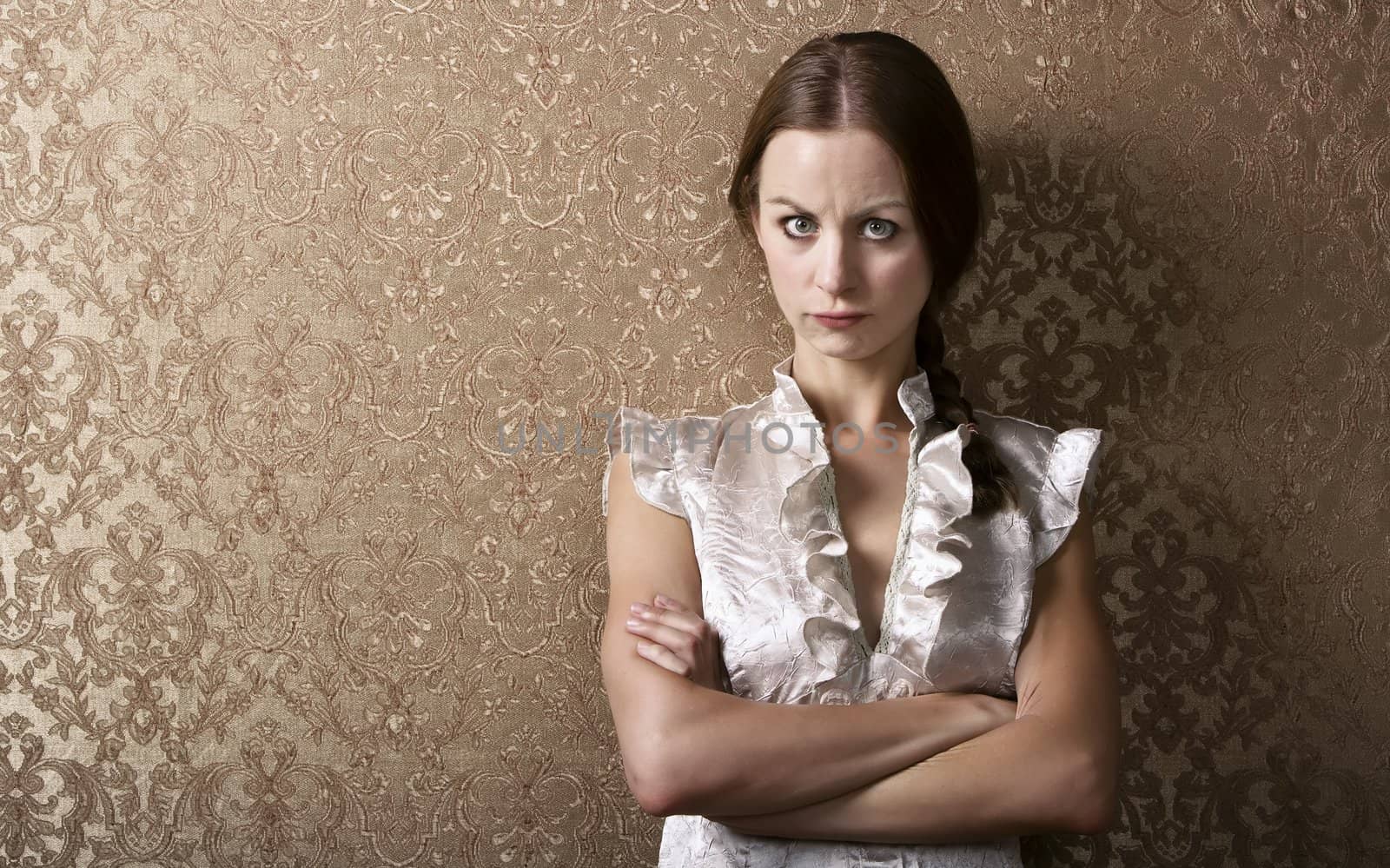 Pretty young woman waiting leaning up against a wall with gold wallpaper