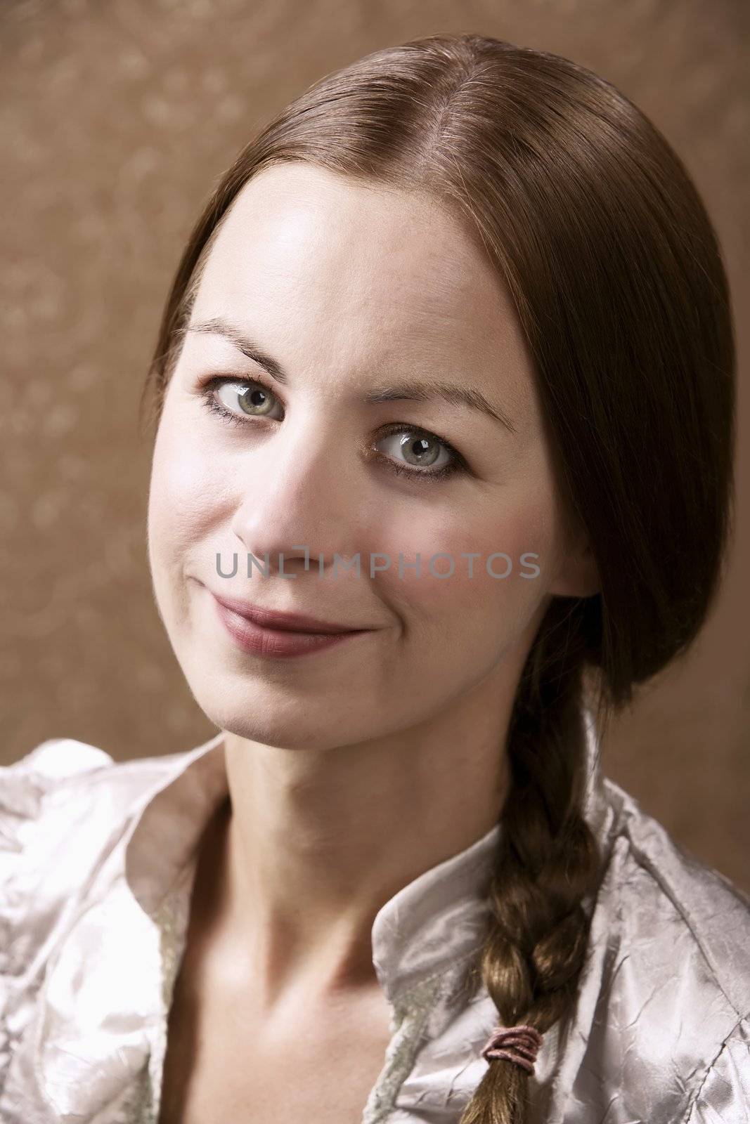 Closeup portrait of an attractive young woman in front of gold wallpaper