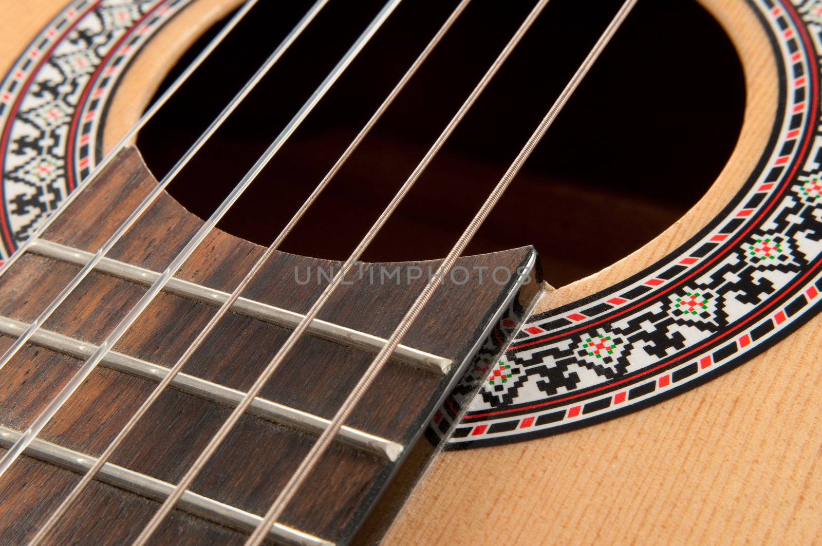 Close up of acoustic guitar strings and rosette.