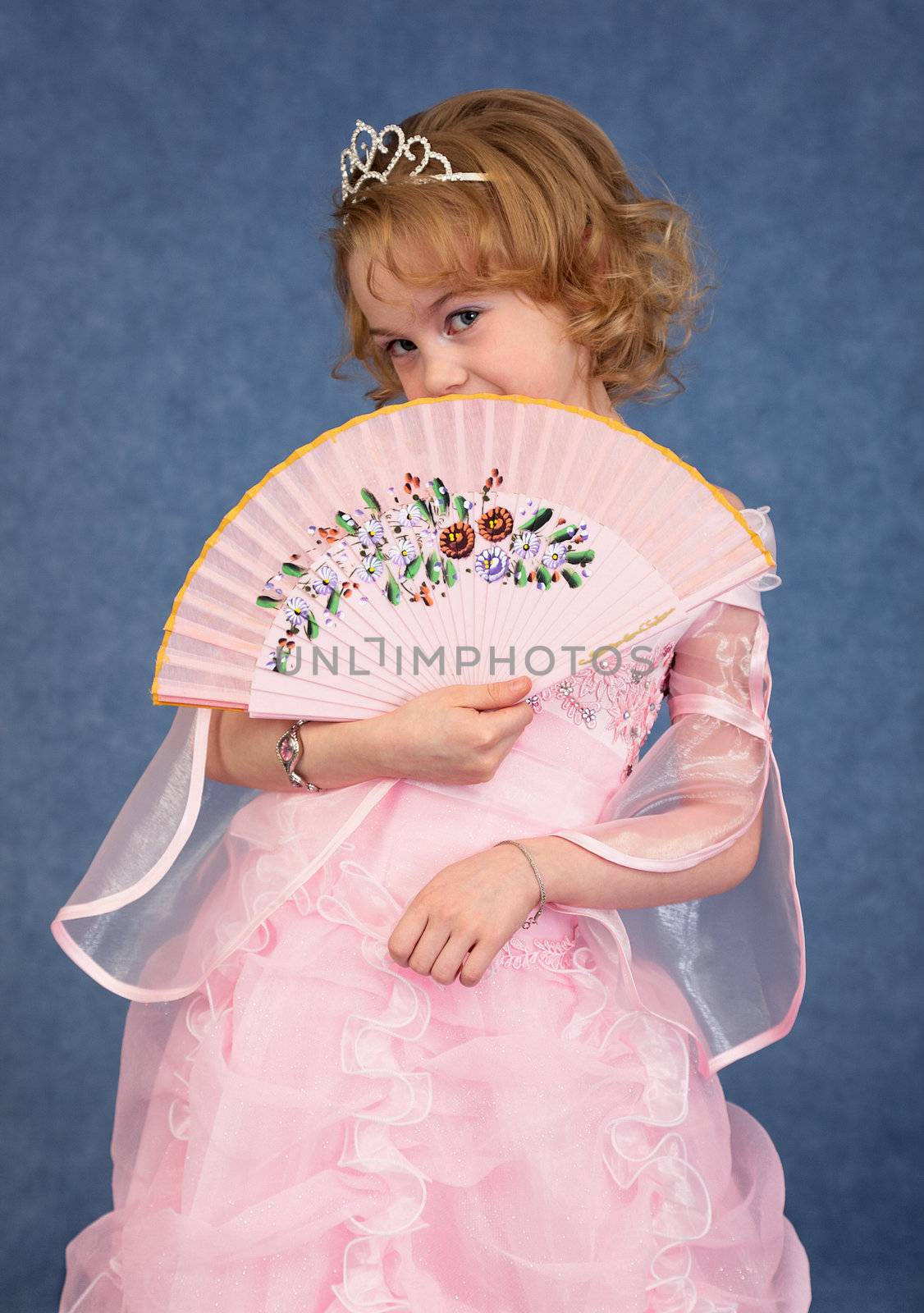 Beautiful little girl in a pink dress with a fan in his hand