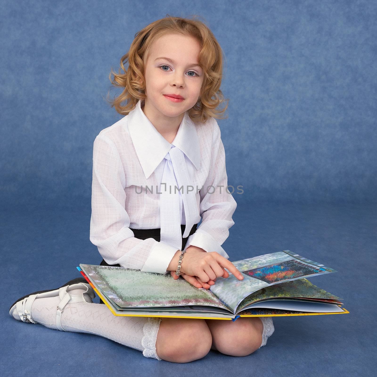 Schoolgirl reading children's book sitting on the floor