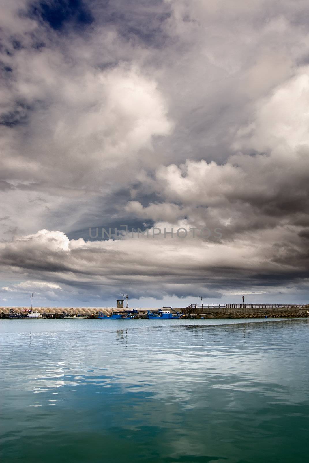 Boats on harbor with dramatic sky before storm coming.