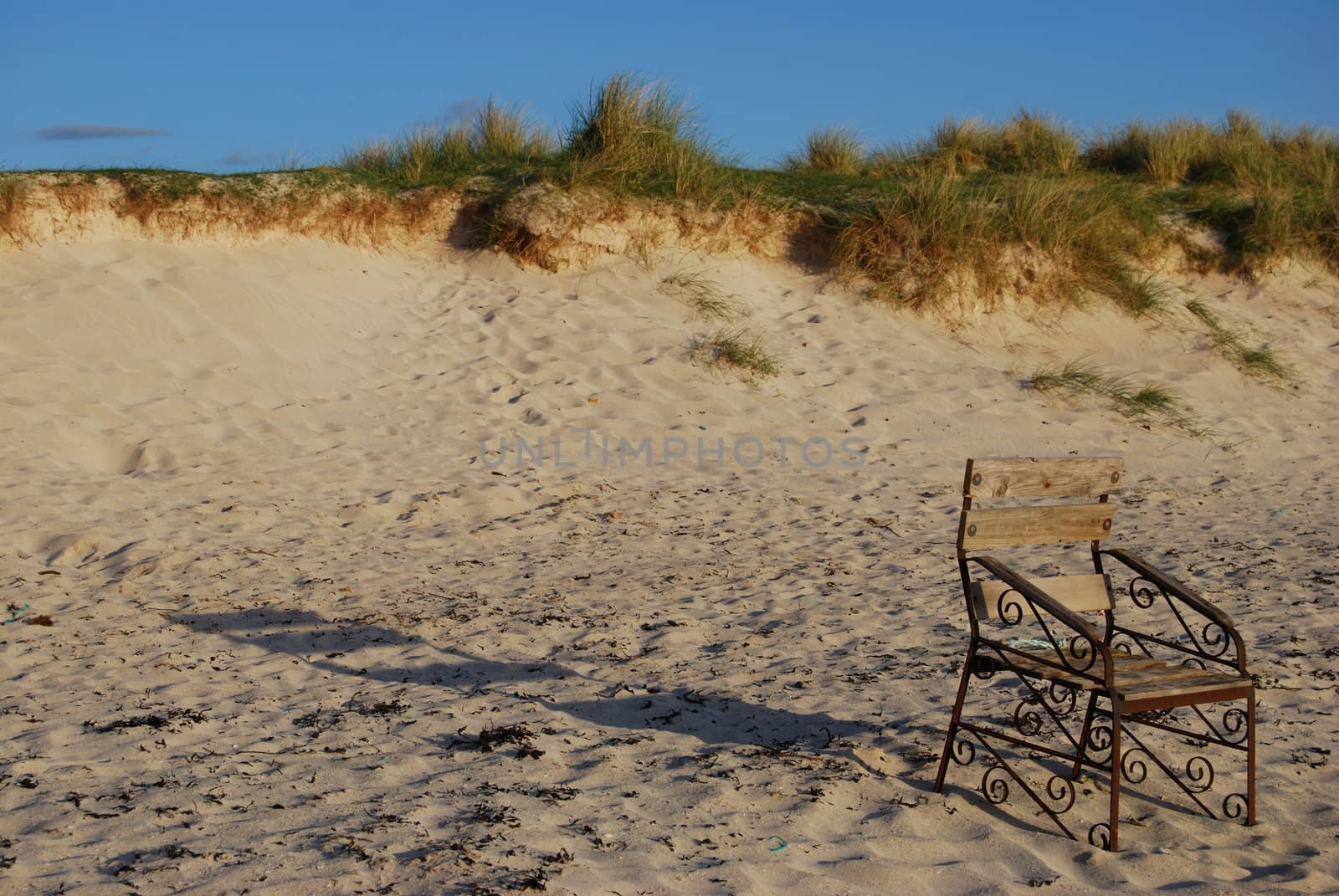 a chair standing on a beach facing the sea