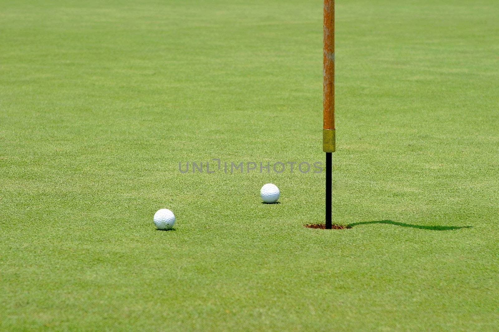 Two golf balls near the flagstick on the green.