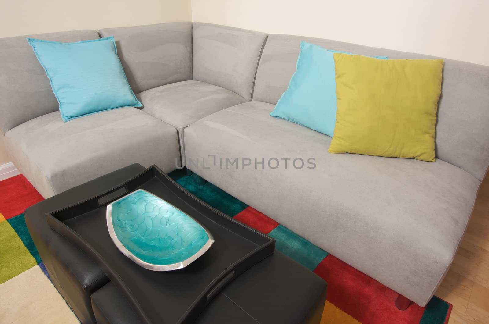 Grey Suede Couch Corner Area with colorful rug and pillows.