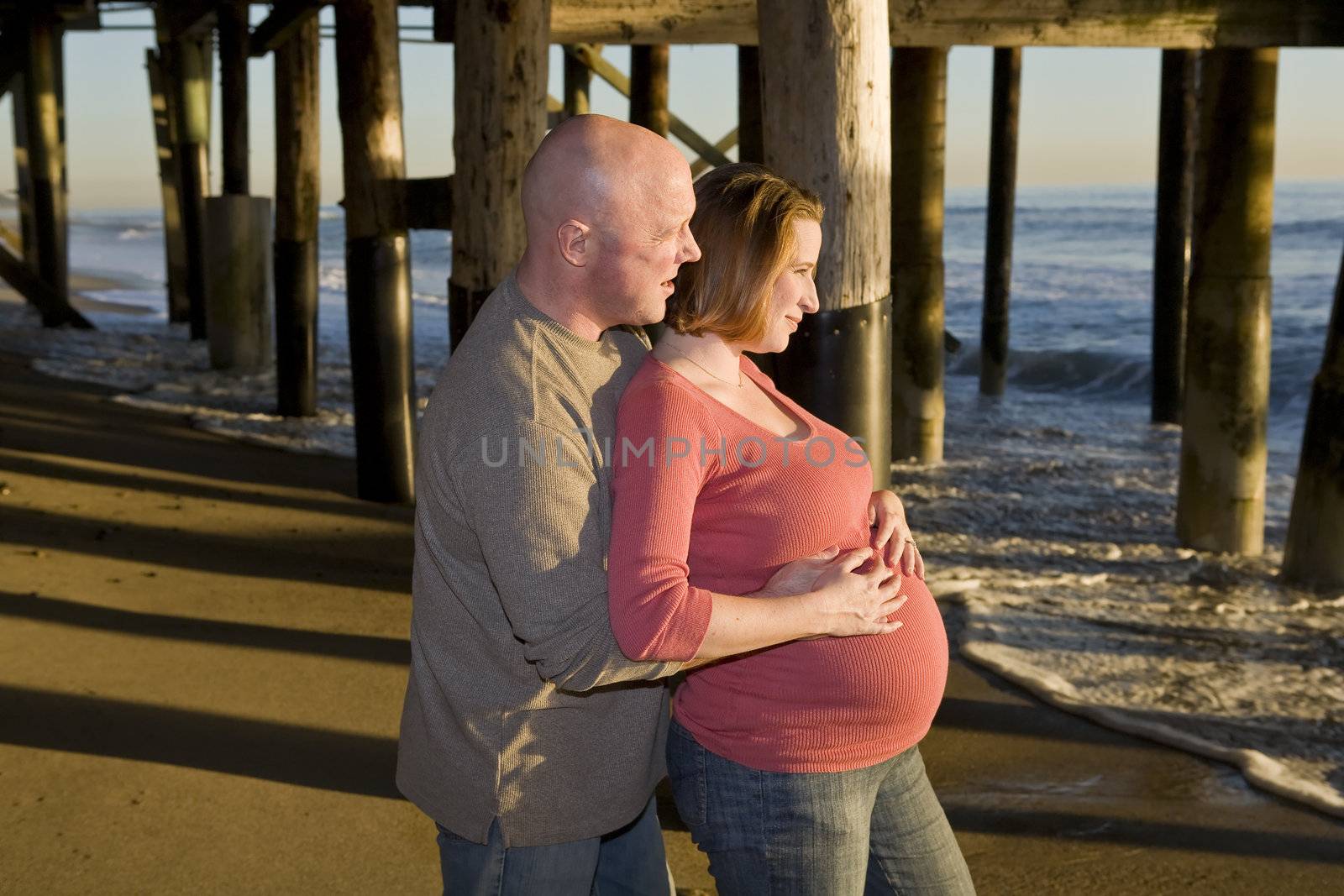 Pregnant Couple looking at the Sunset on Beach