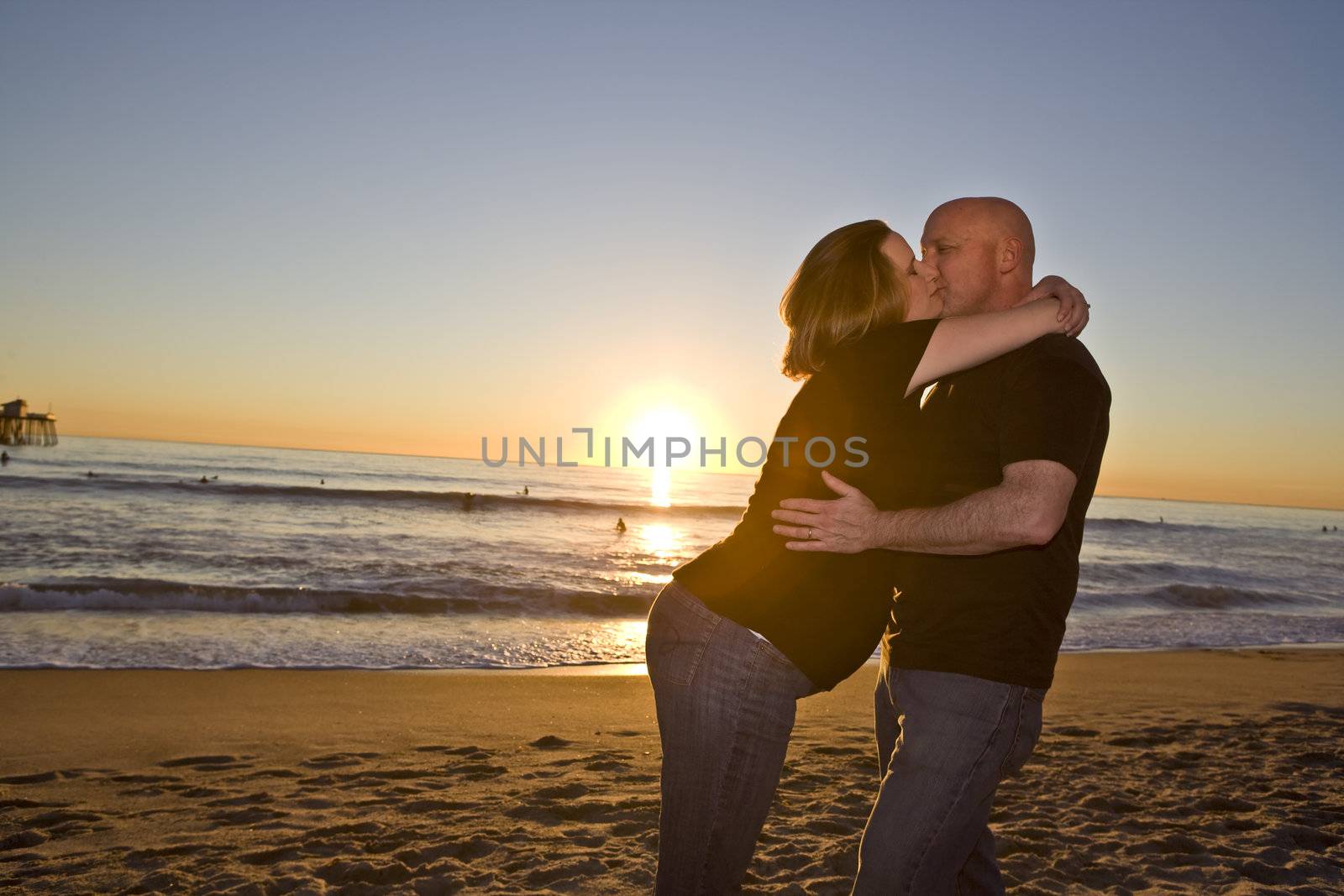 Young Pregnant Couple on the Beach at Sunset