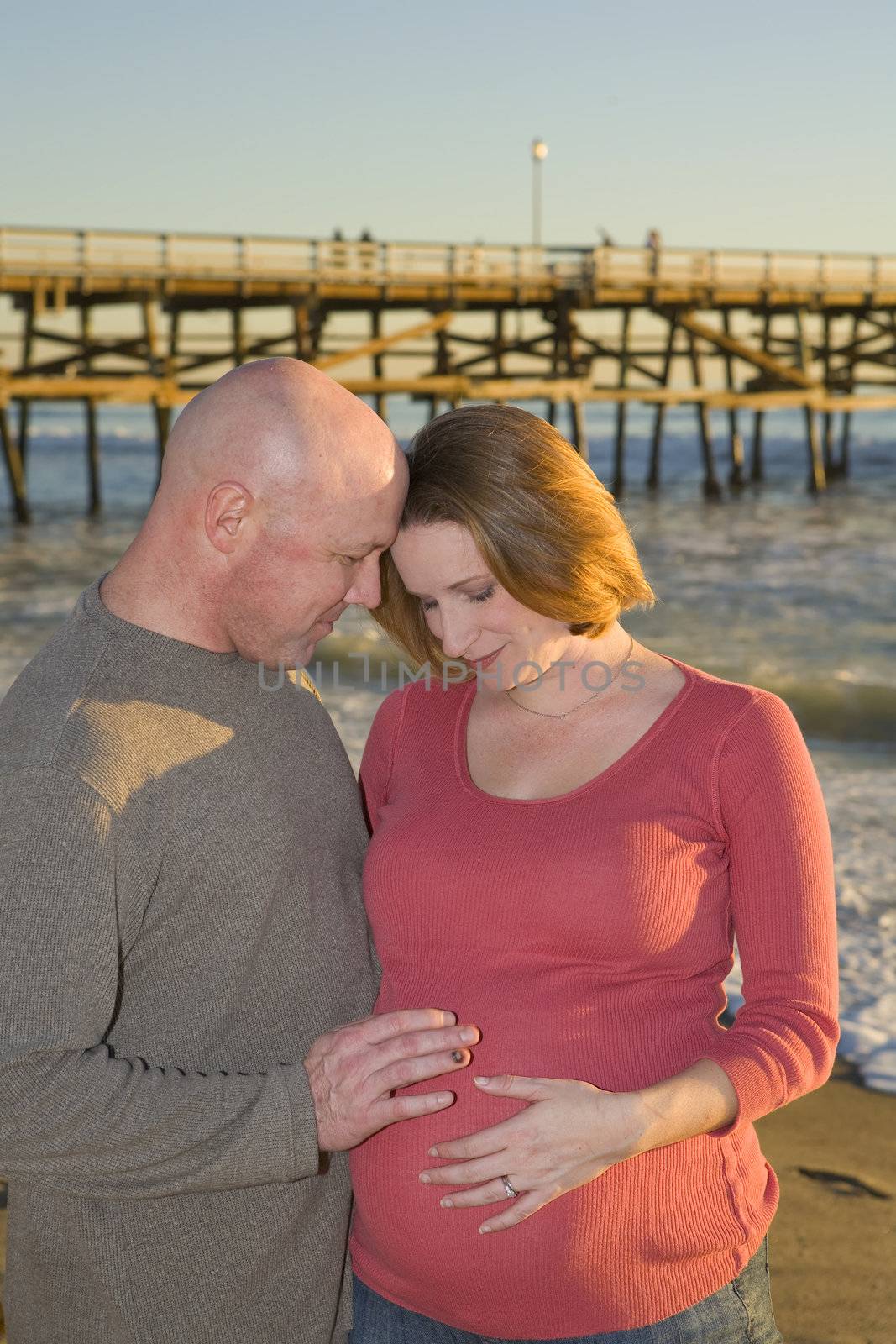 Young Pregnant couple on the Beach at Sunset