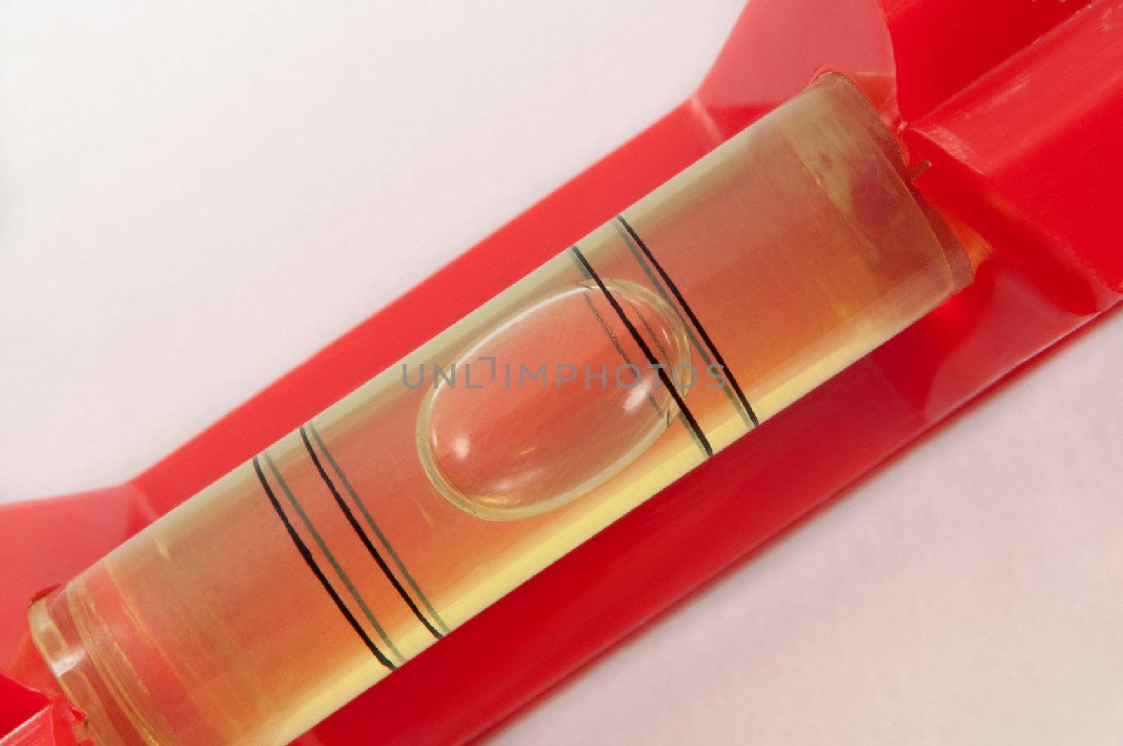 Close up of a red spirit level captured diagonally across the image with white background.