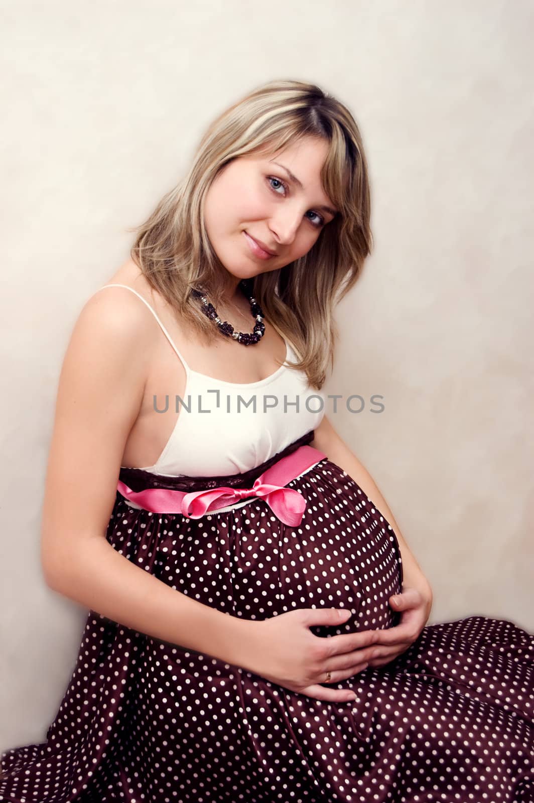 Close-up of pretty pregnant woman with pink ribbon, third trimester