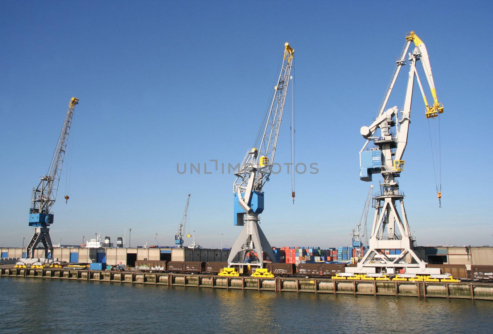 Harbor cranes, containers and train cars on a dock in Rotterdam