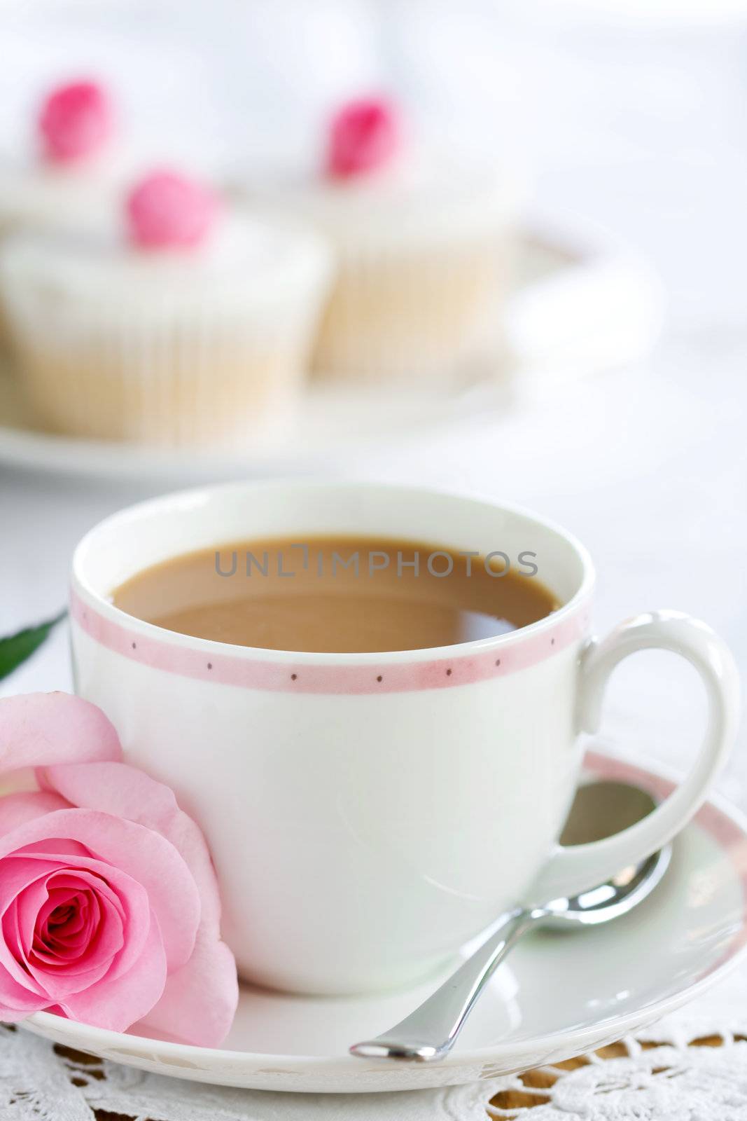 Cup of tea served with a rose and cupcakes