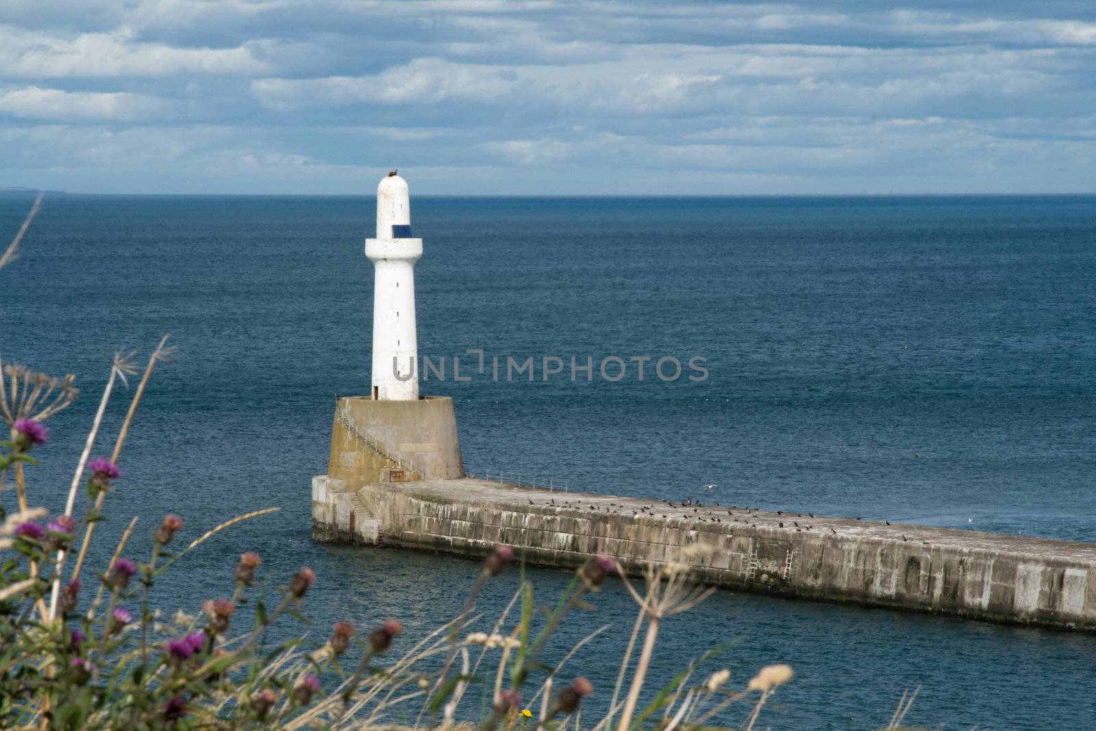 Lighthouse on a sunny day, against a stormy sky