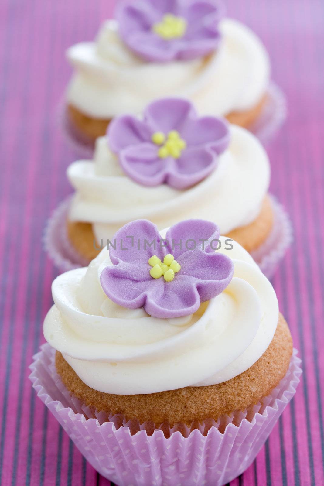 Row of cupcakes decorated with purple sugar flowers