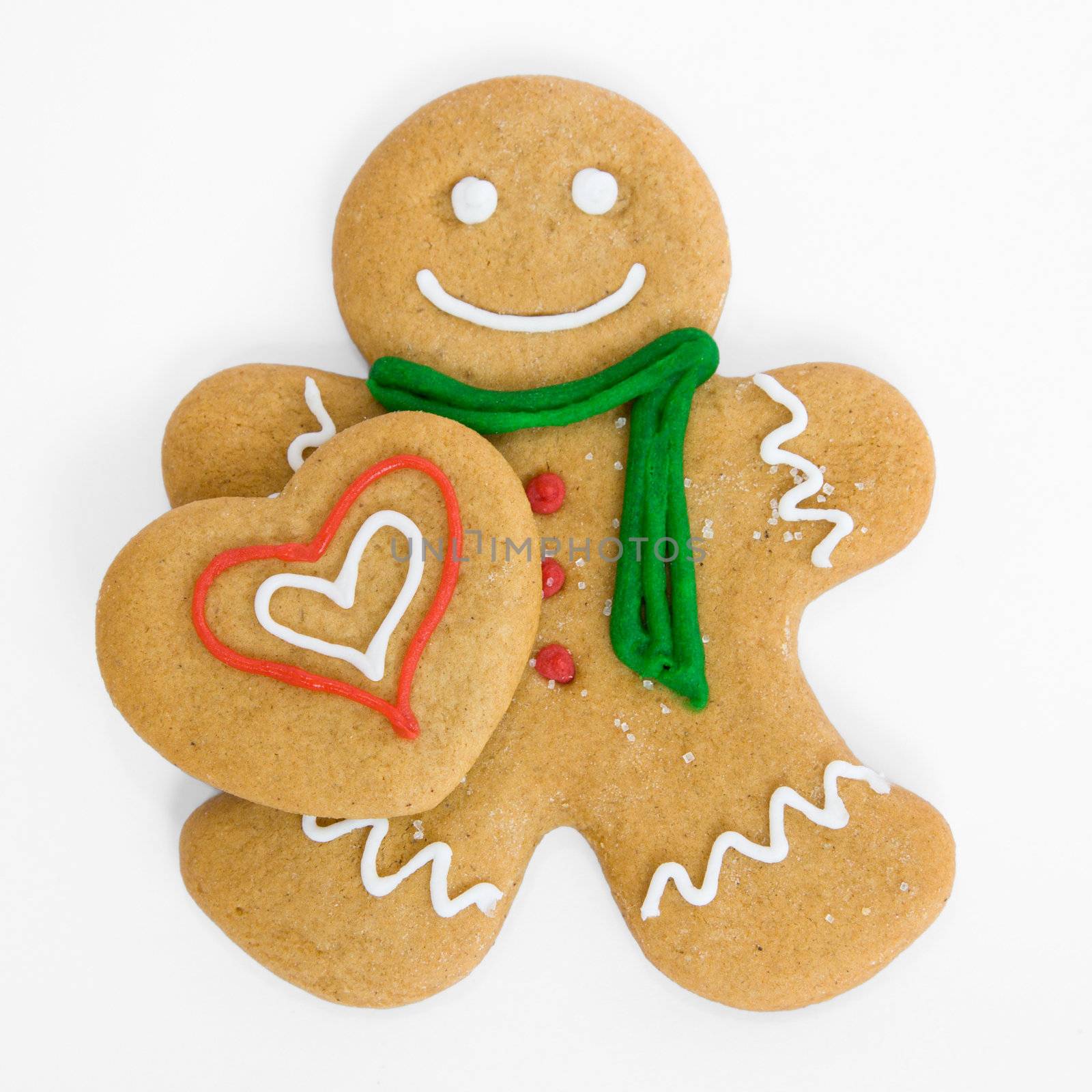 Smiling gingerbread man holds iced gingerbread heart