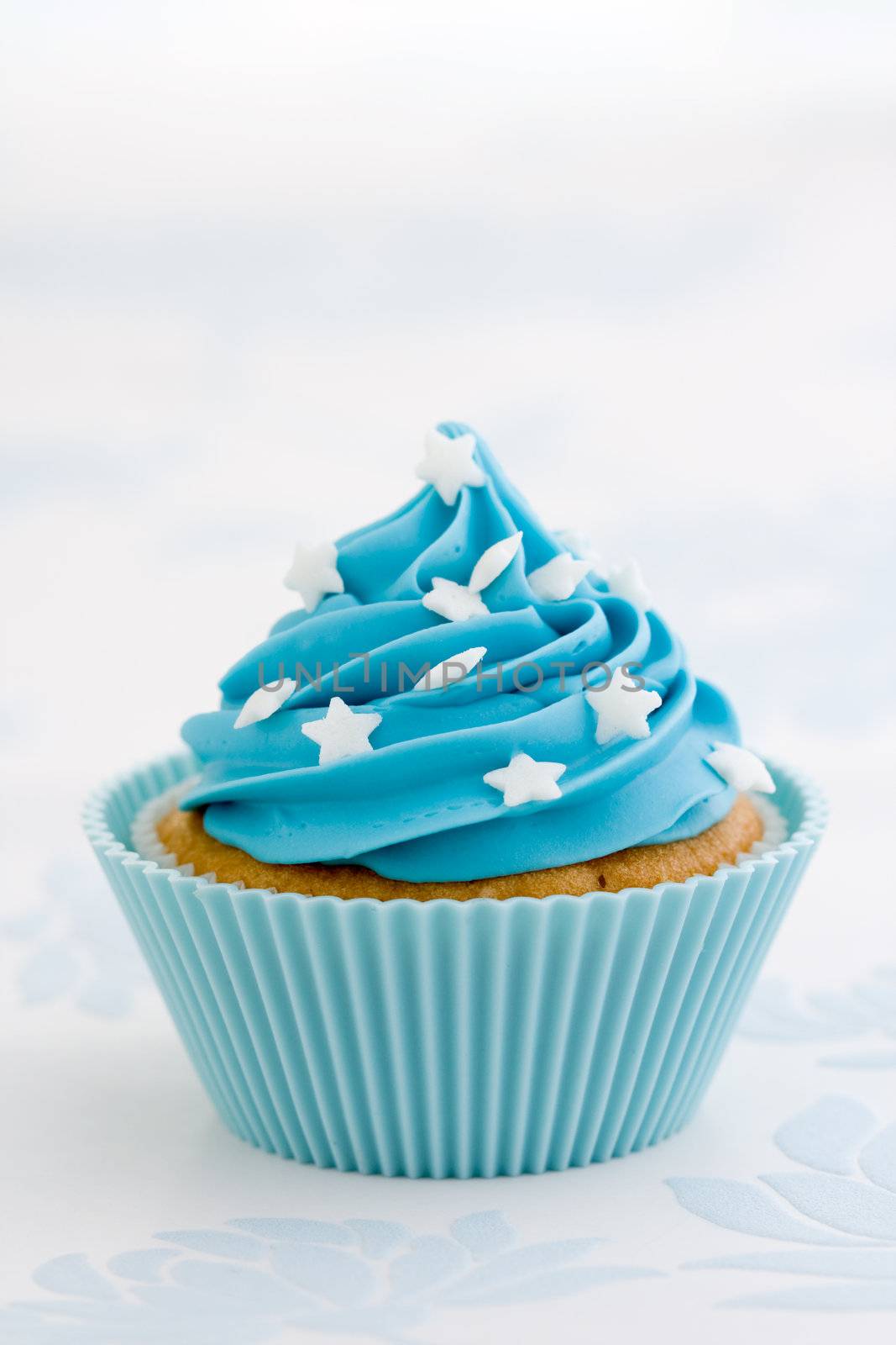 Cupcake decorated with blue frosting and white sugar stars
