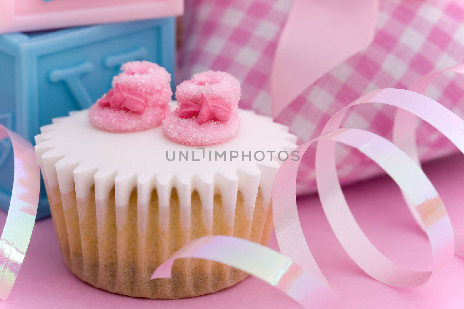 Mini cupcake decorated with tiny pink sugar booties