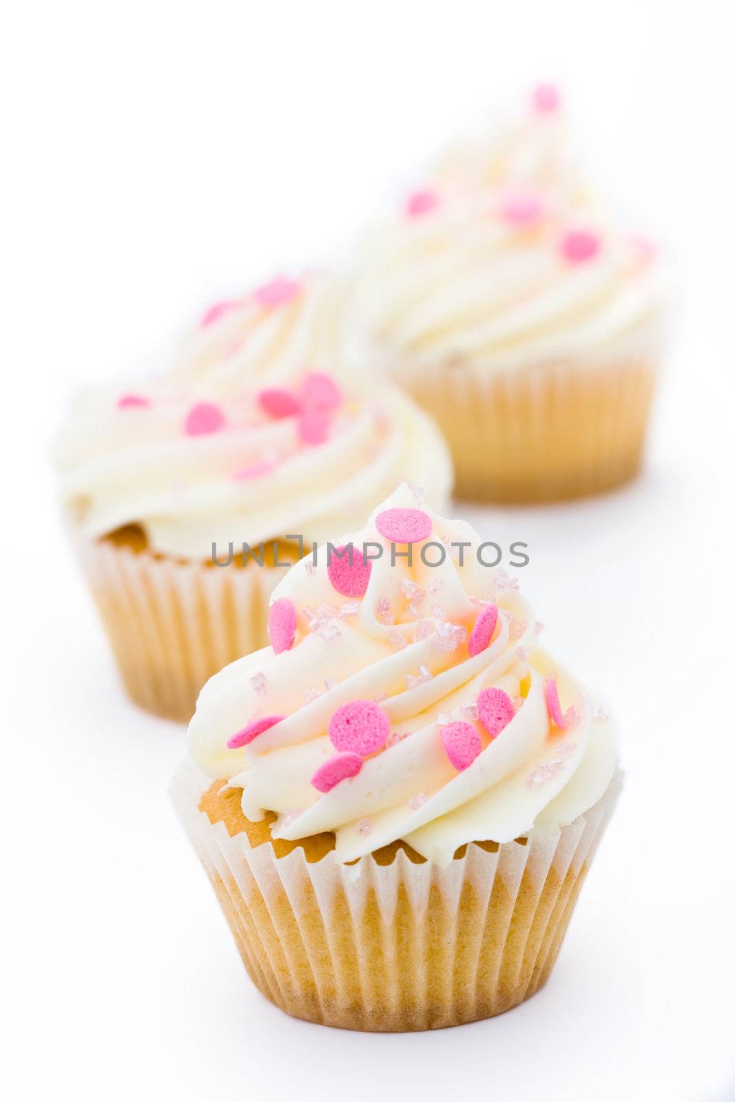 Trio of pink and white cupcakes against a white background