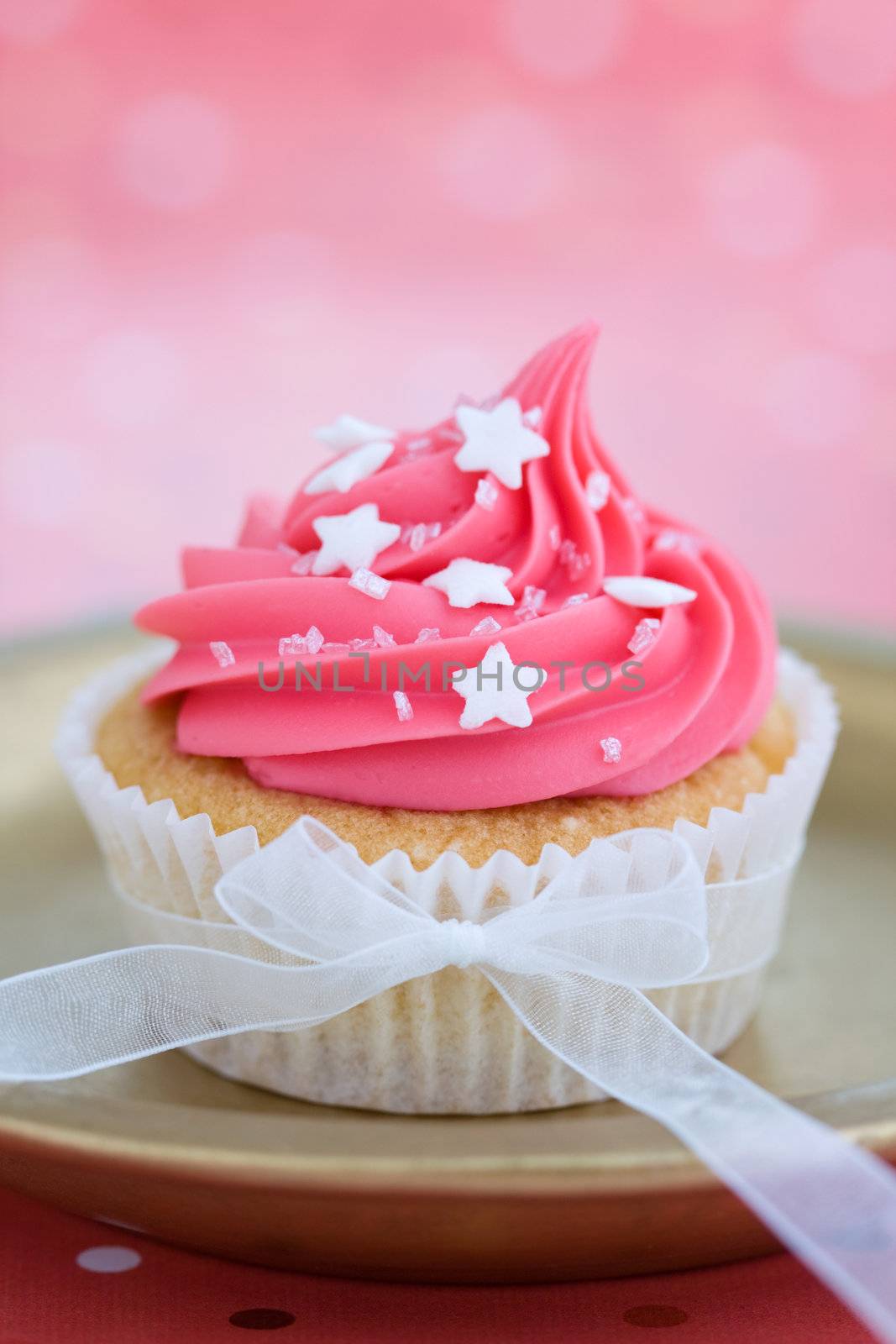 Cupcake decorated with pink frosting and an organza ribbon