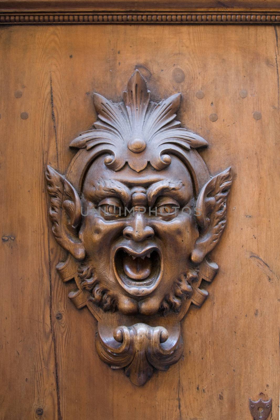 Carved gargoyle adorning a wooden door in Siena, Italy