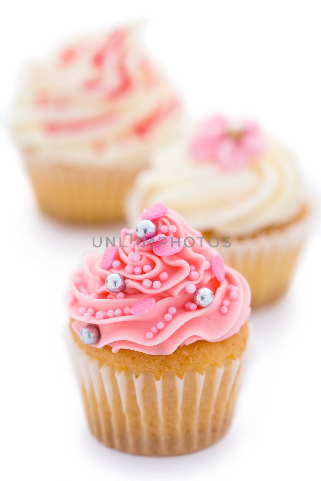 Trio of pink and white cupcakes against white