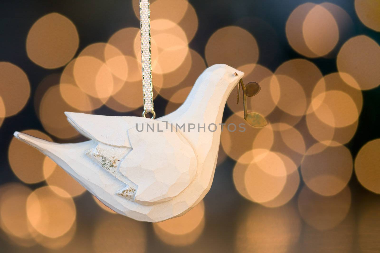 Wooden dove hangs in front of de-focused christmas lights