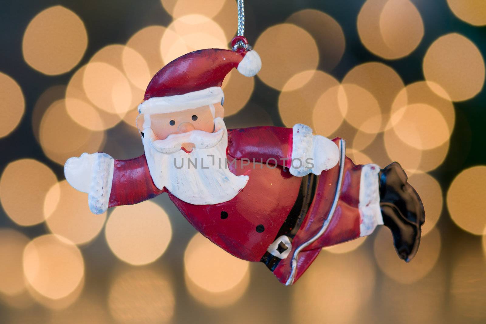 Santa Claus decoration hangs in front of de-focused christmas lights